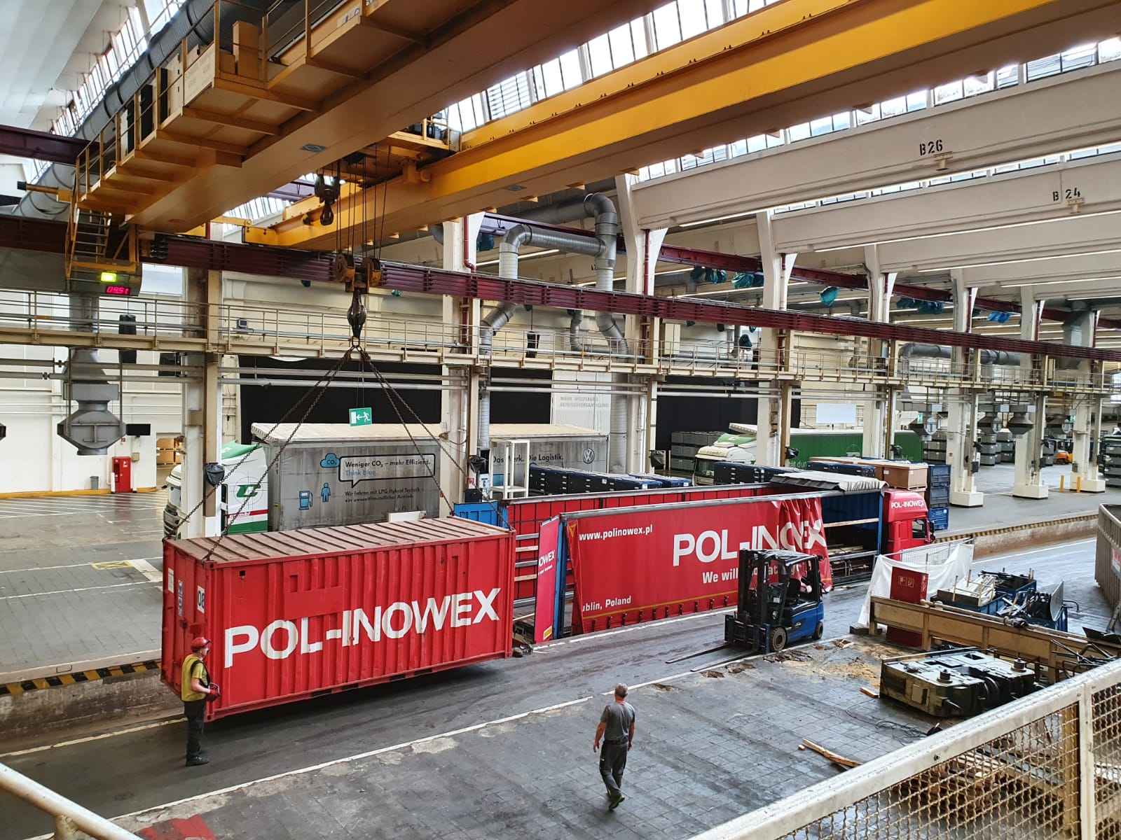 Container lifted by overhead crane inside a hall